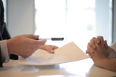 a person sitting at a table with a contract and a pen